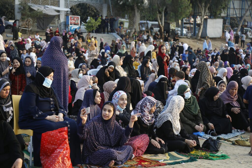 A large group of worshippers gathered outdoors on a street in Gaza City for Eid prayers, kneeling in rows under daylight. Photo by Musa Alzanoun via Pexels.