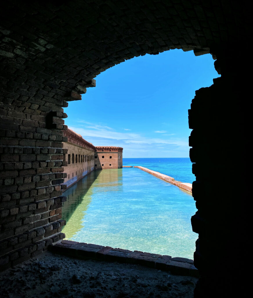 View of Fort Jefferson at Dry Tortugas National Park framed through a brick archway, with turquoise water and the Gulf of Mexico stretching to the horizon.