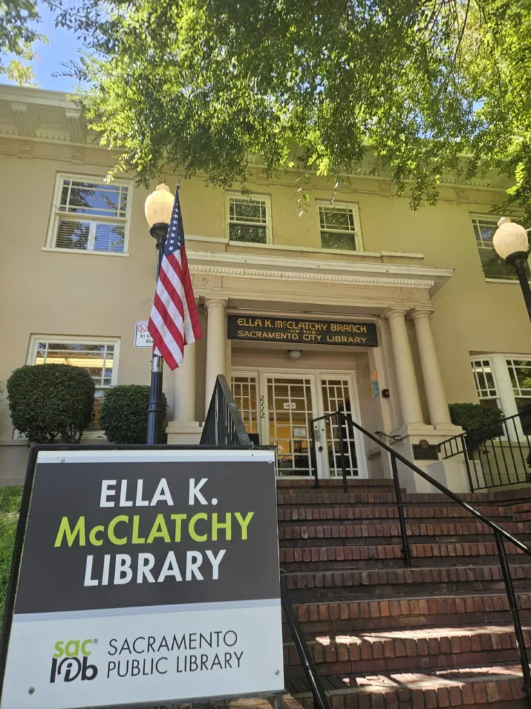 The Ella K. McClatchy Library, a yellow historic home in Sacramento, California, with brick steps, white columns, and its name carved above the entrance.